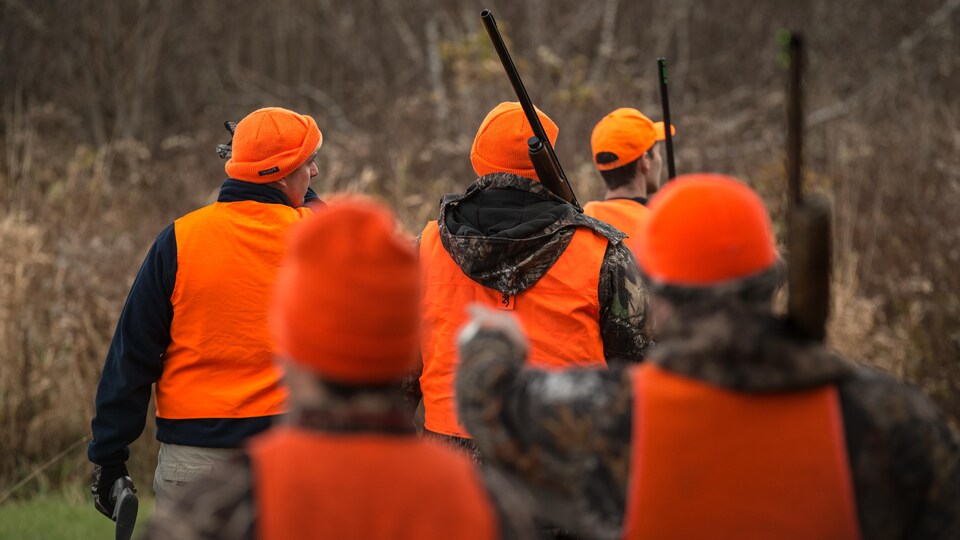 Des chasseurs à la carabine marchent dans le bois.