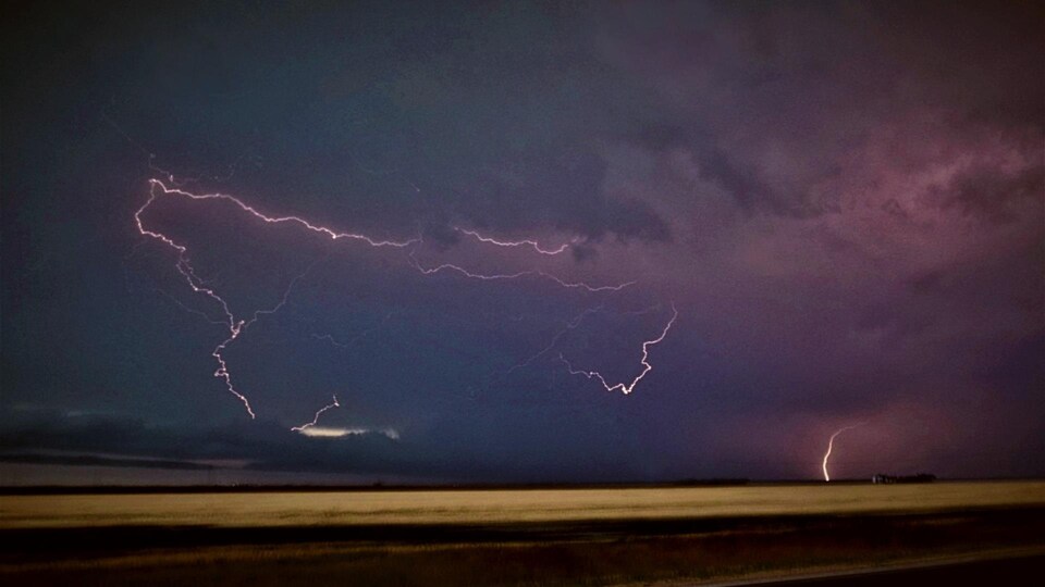 La foudre jaillit au dessus un champ des Prairies.