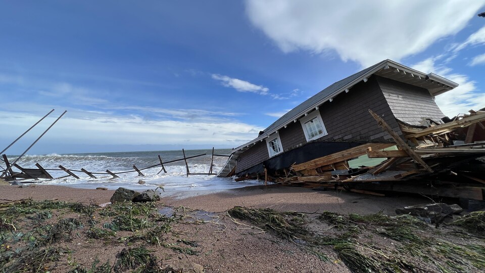 Une grosse maison en partie effondrée dans la mer. 