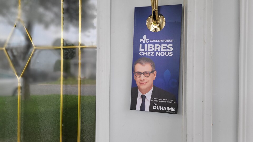 Un pamphlet électoral aux couleurs du Parti conservateur du Québec sur une poignée de porte.