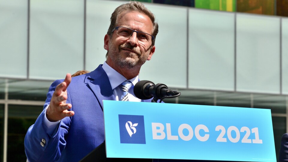 Yves-François Blanchet parle et gesticule dehors devant un édifice.