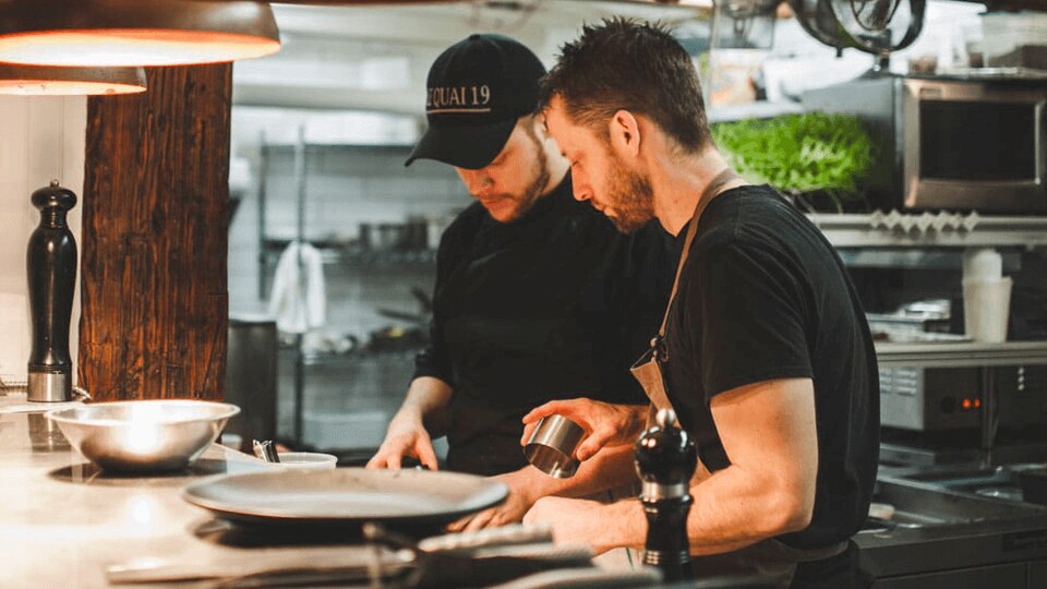 Deux hommes dans les cuisines d'un restaurant.