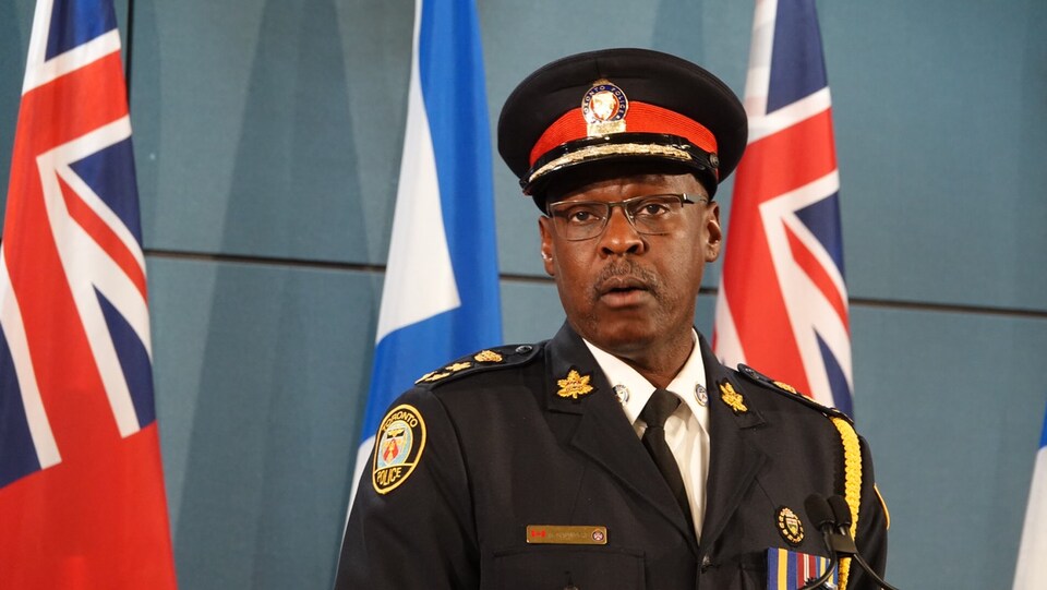 Photo d'un homme portant un uniforme et une casquette de policier devant un micro.