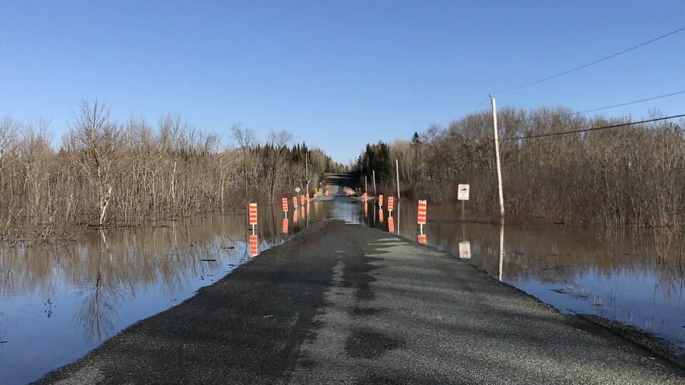 Un rang de campagne où on a placé des panneaux réfléchissants là où la chaussée est inondée.