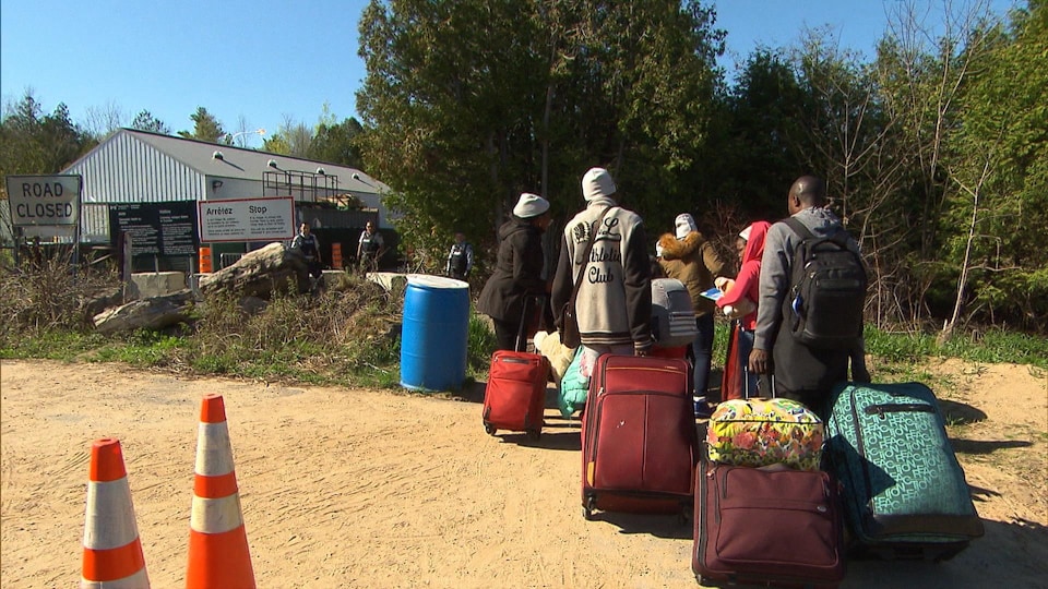 Des migrants se rendent au Canada par le chemin Roxham alors que des agents de la GRC les attendent de l'autre côté de la frontière. 