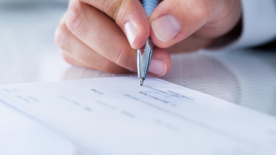 A hand holding a pen indicates a check.