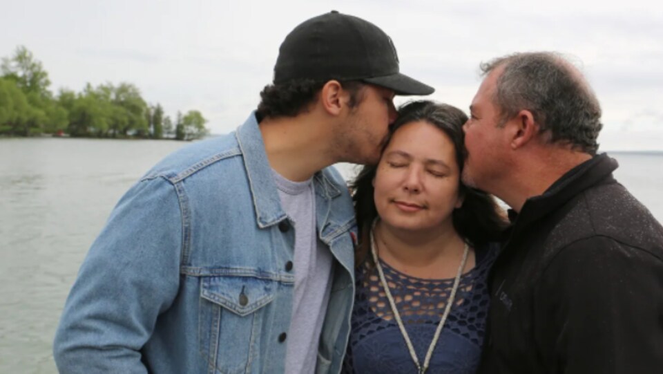 Le mari de Cheryl-Anne Labrador-Summers et l'un de ses fils l'embrassent sur le quai près de leur maison au bord du lac à Georgina, en Ontario.