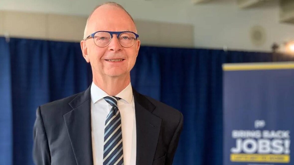 Ches Crosbie pose en complet les deux mains dans le dos.