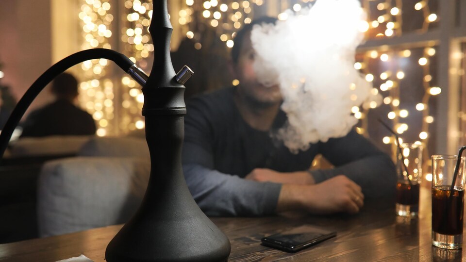 Un homme fume de la chicha dans un bar.