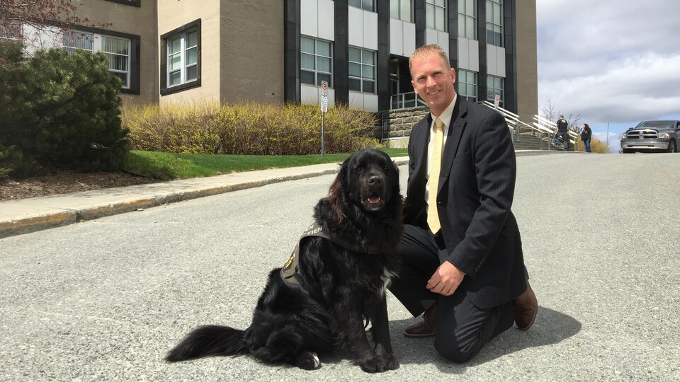 Un chien pose avec son maître policier, devant le palais de justice de Rouyn-Noranda.