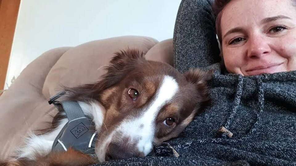 Autoportrait de Megan Bolen et son chien assis sur un divan.