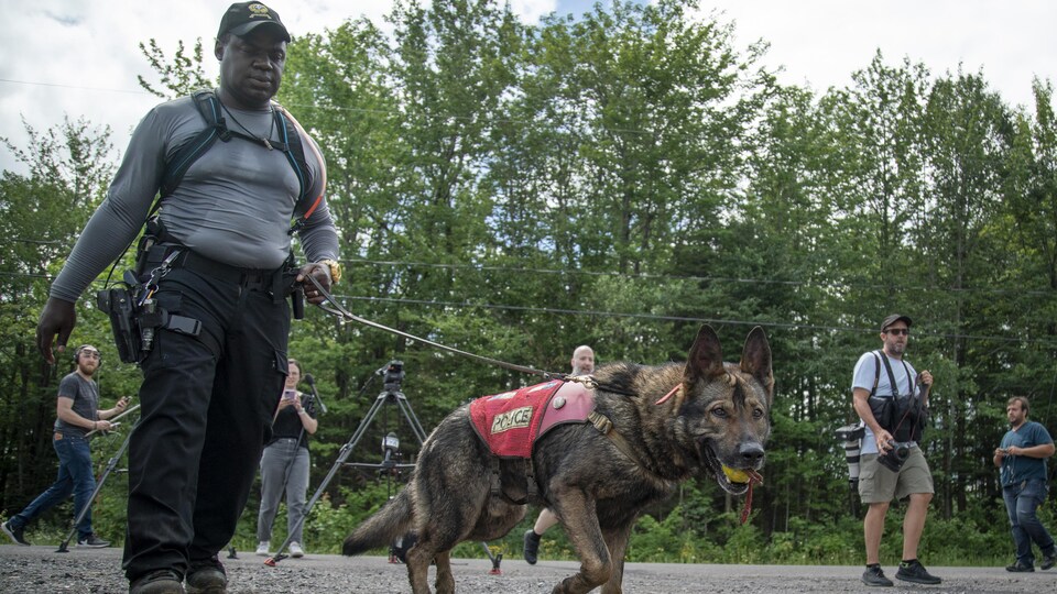Un policier tient un chien en laisse.