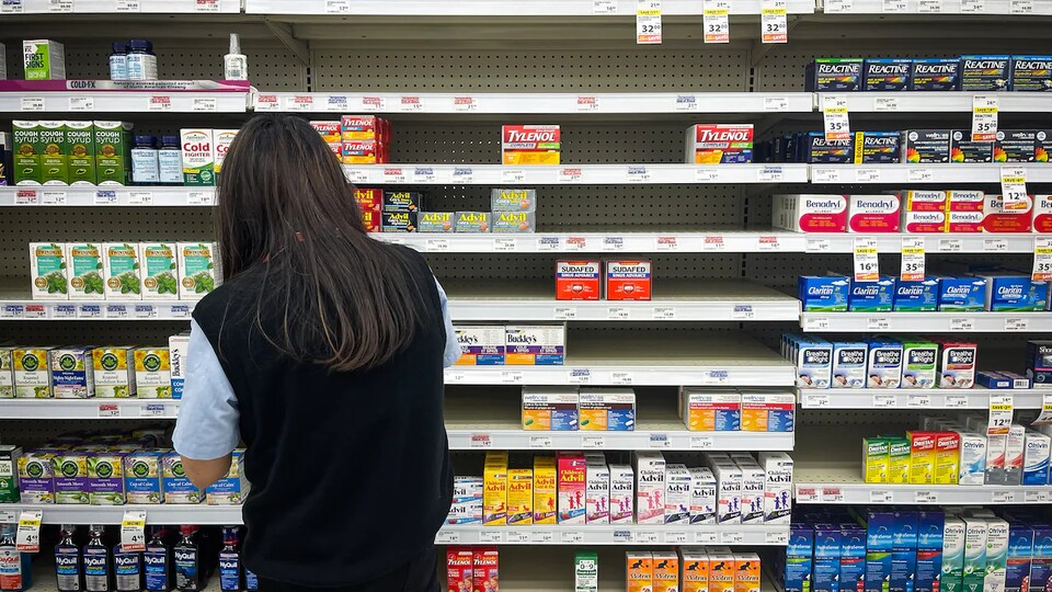 Une personne devant une étagère clairsemée de la pharmacie.