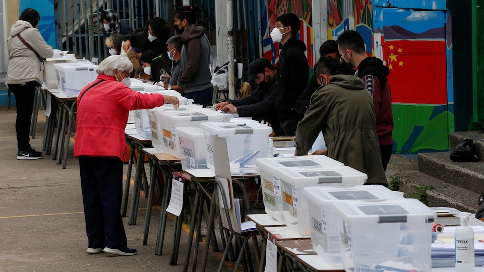 Une femme vote en plein air, au Chili.