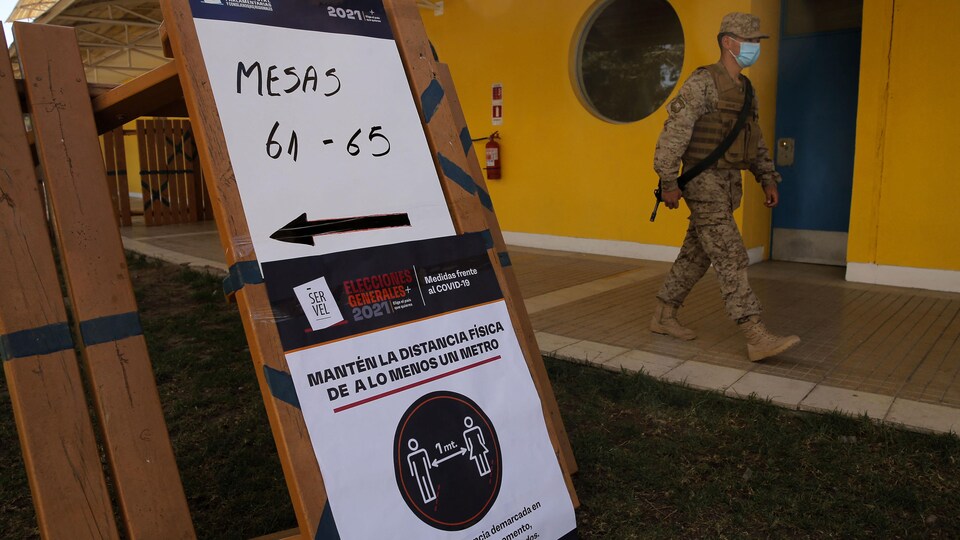 Une pancarte et un soldat devant un bureau de vote.