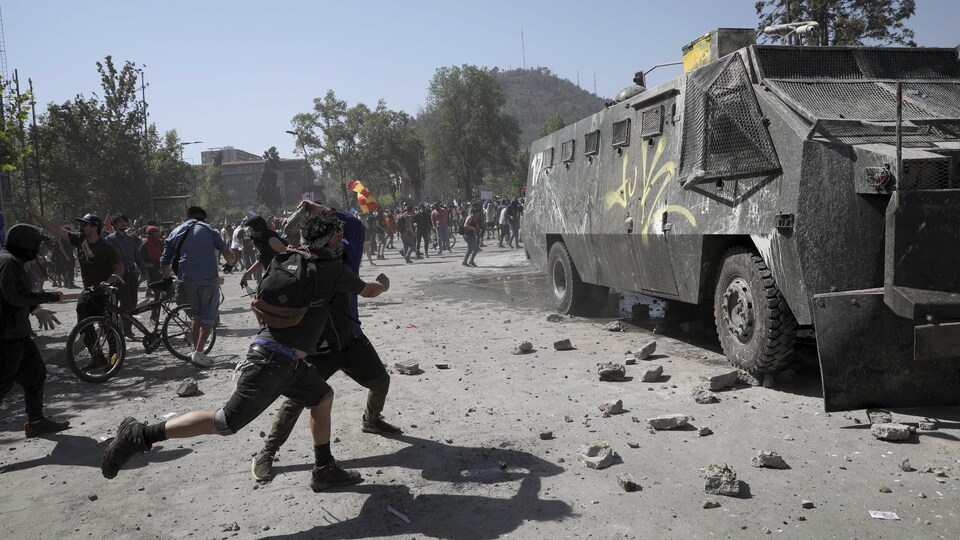 Des manifestants lancent des pierres sur un canon à eau de la police à Santiago.