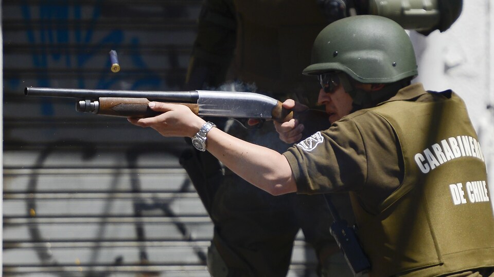 Un  policier utilise son arme lors d'une manifestation anti-gouvernement à Valparaiso.