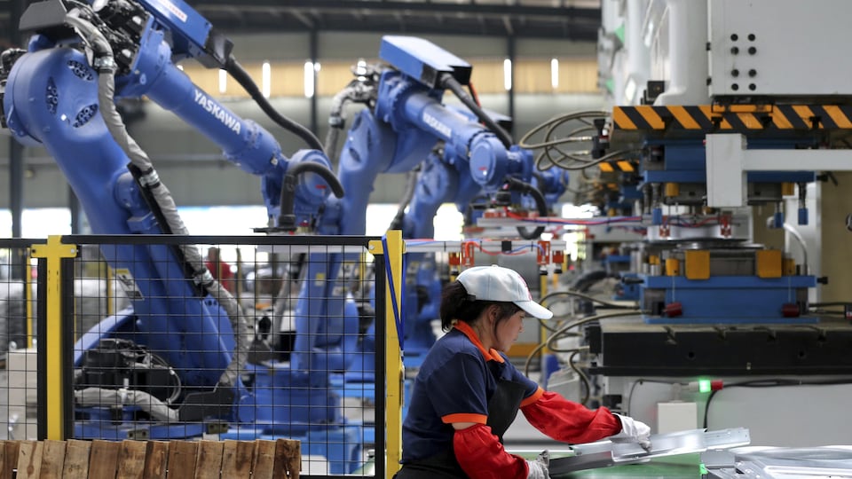 Une employée dans une usine assistée de robots