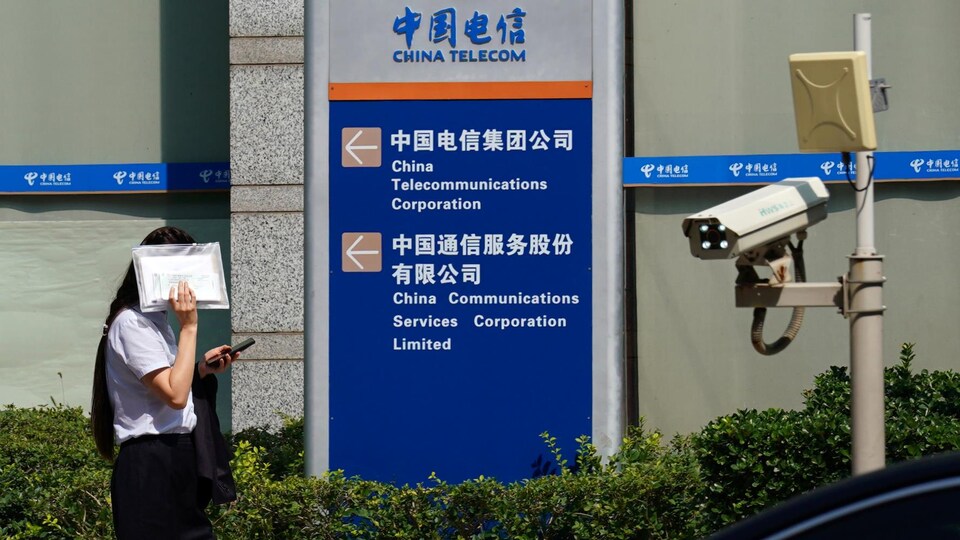 Une femme cache son visage en passant devant les bureaux de China Telecom, à Pékin.