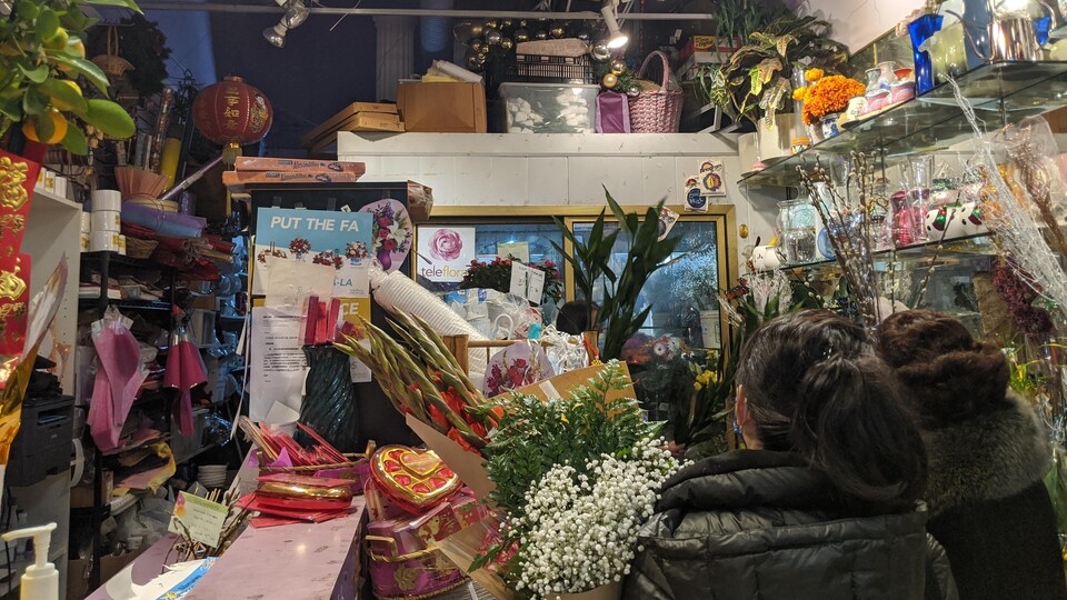 Dans la boutique, deux clientes avec des bouquets d'arrangements floraux dans les mains.