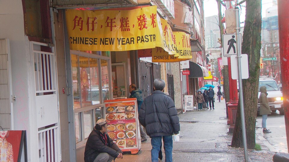 Une rue avec des magasins chinois et des gens qui marchent.