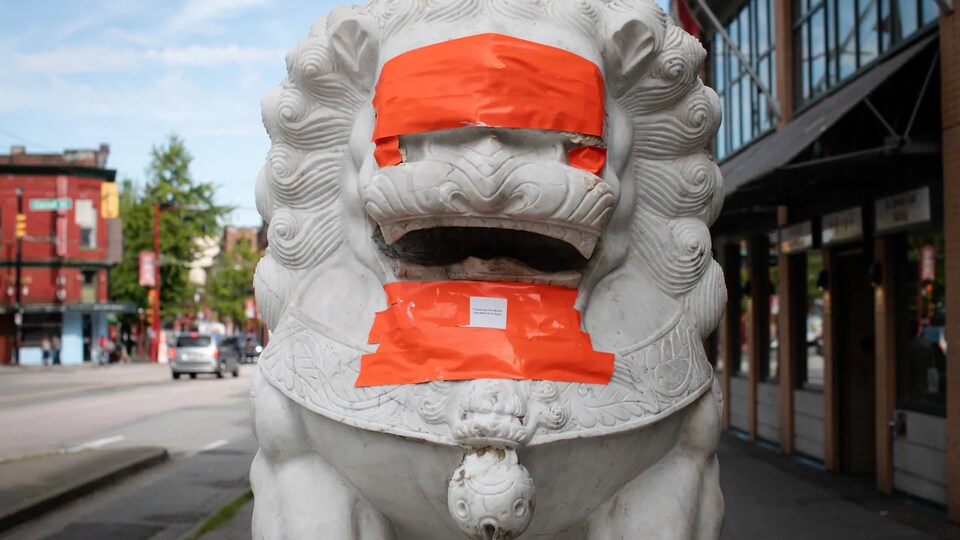 Une statue de lion recouverte de ruban adhésif orange.