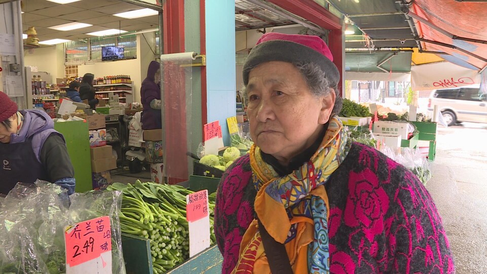 Hui Qing Chen et un marché derrière elle avec des légumes.