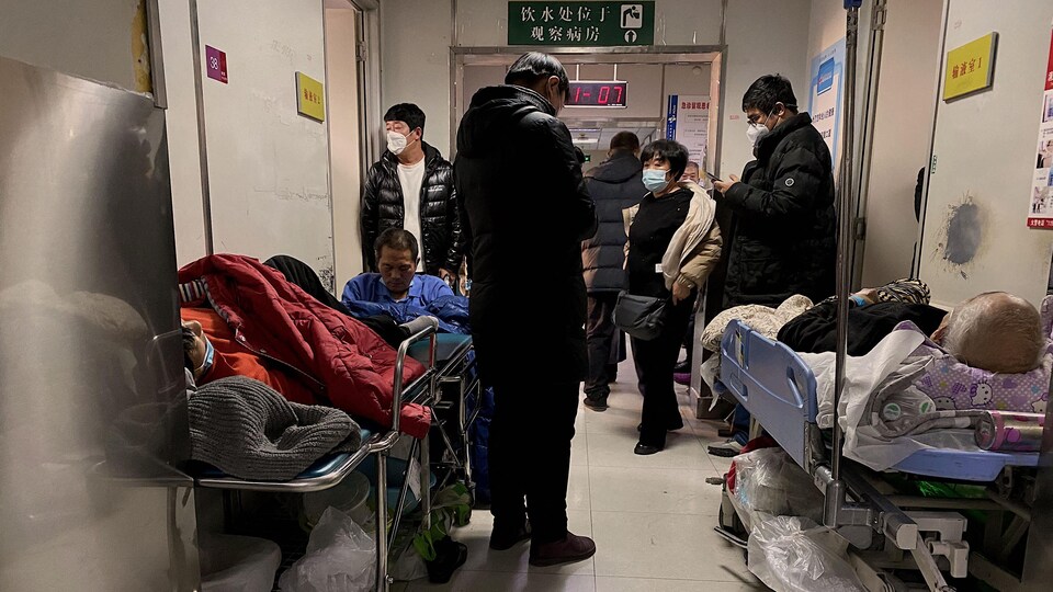 Des patients atteints de la COVID-19 attendent sur des brancards dans le corridor d'un hôpital.