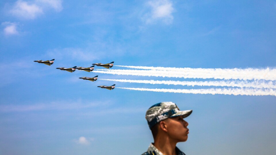 Des avions militaires volent dans le ciel pendant qu'un homme regarde dans la direction opposée.