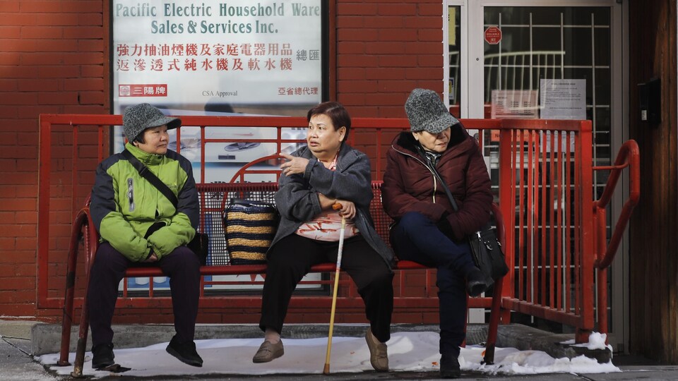 Trois femmes d'origine asiatique assises sur un banc dans le quartier chinois de Calgary, en Alberta.