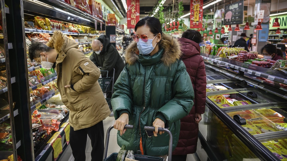 Trois Chinois portent des masques dans une allée d'épicerie. 
