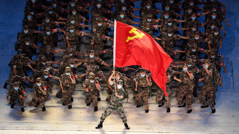 Un homme agite un drapeau chinois devant un groupe de soldats.