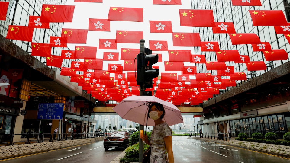 Une femme tient un parapluie et marche sous les drapeaux.