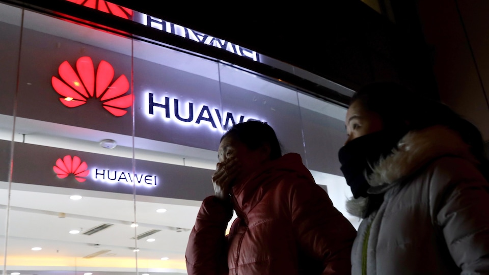 Deux femmes passent devant un magasin du géant chinois Huawei.