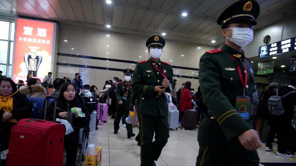 Des policiers portant des masques médicaux marchent dans une gare de Shangai.