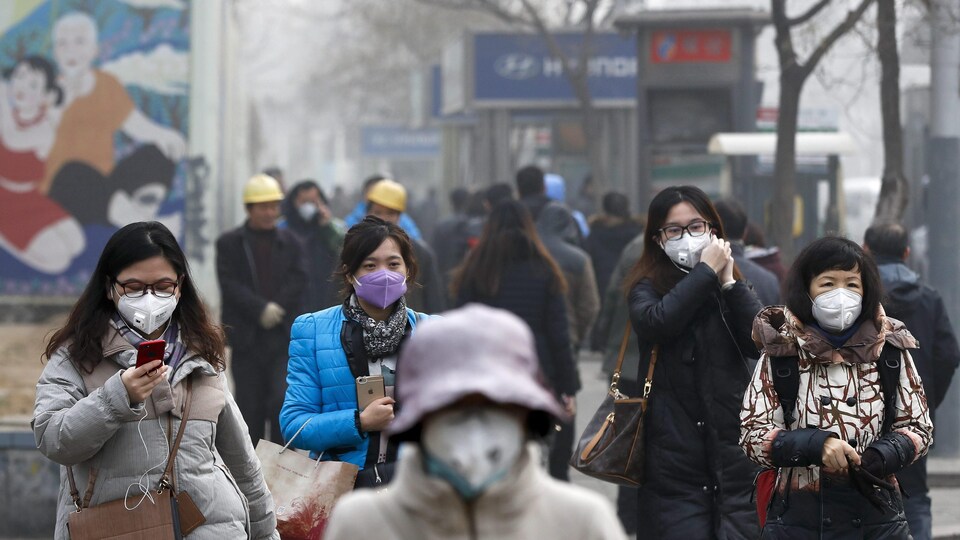 Le 20 décembre 2016 à Beijing, en Chine, des femmes marchent dans la rue avec un masque de protection afin de se protéger contre la pollution.