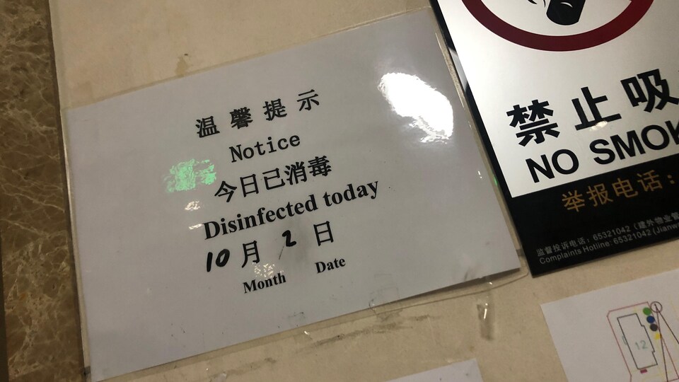 Une petite affiche, placée près d'un ascenseur, indique que le bâtiment a été désinfecté durant la journée. Pékin, 2 octobre 2020.
