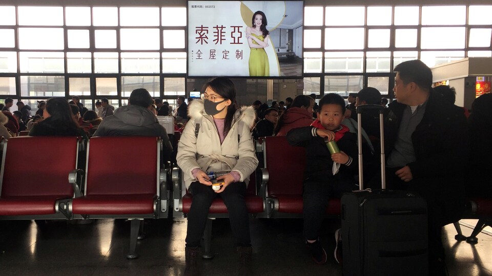 Une femme portant un masque attend de prendre le train pour Wuhan, en Chine.