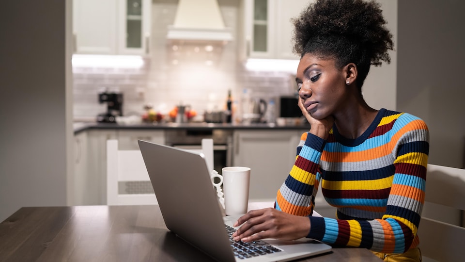 Une femme noire à la recherche d'un emploi devant son ordinateur.