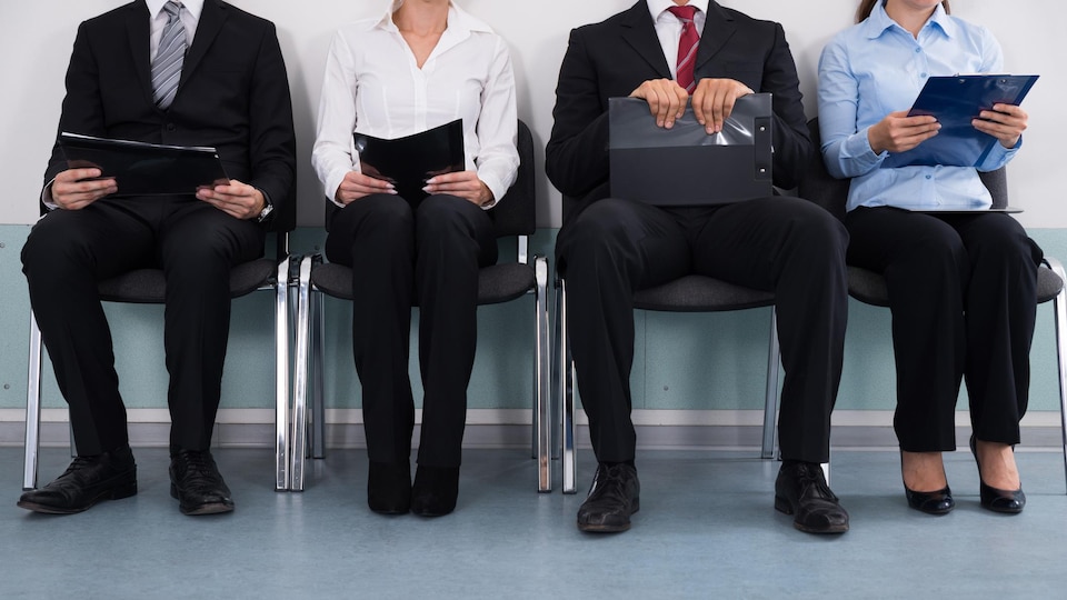 Des candidats attendent pour une entrevue assis en rangée.