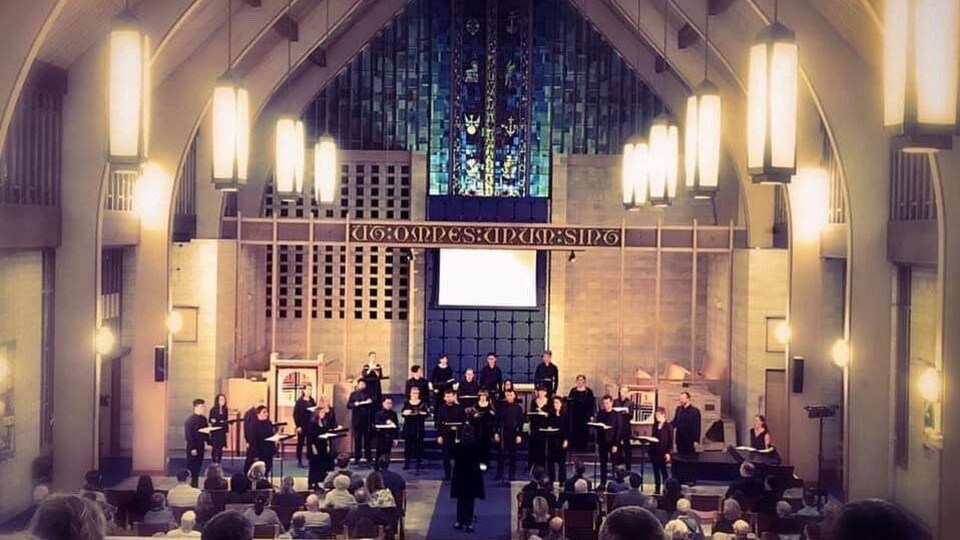 Une chorale chante au sein d'une église devant un public.
