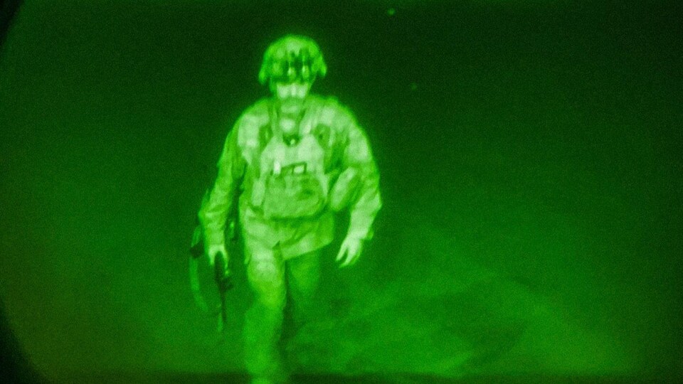 Un militaire en habit de combat monte dans un avion.