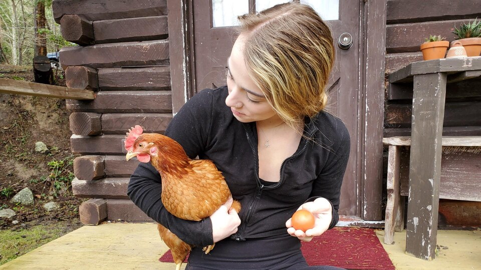 Stef Lowey tient une poule rousse et un œuf.