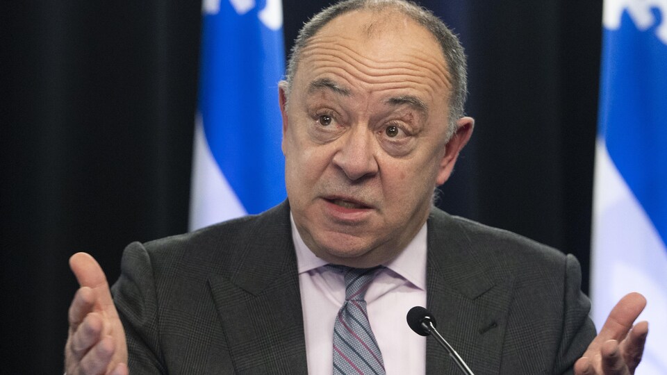 Plan rapproché de Christian Dubé devant des drapeaux du Québec