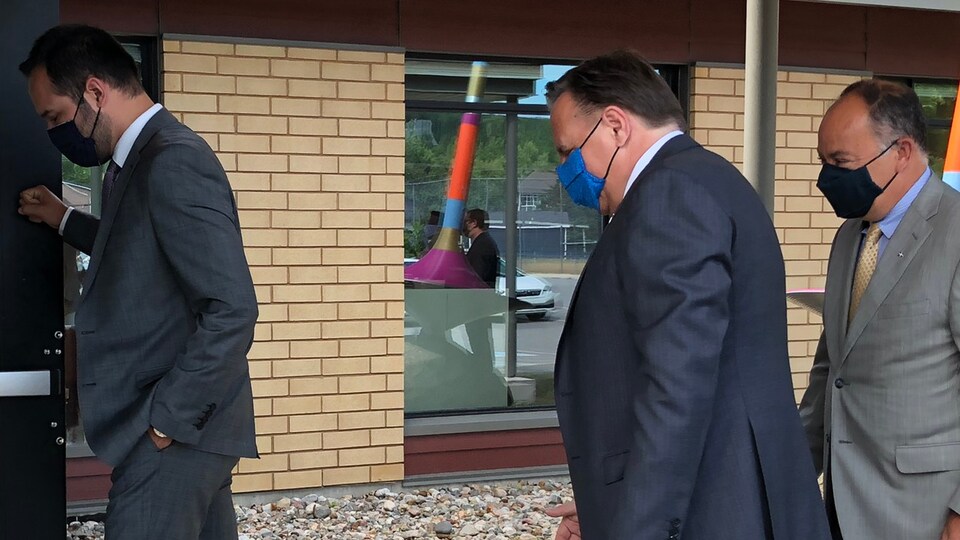 Mathieu Lacombe, François Legault et Chrisitan Dubé portant des masques alors qu'ils entrent dans un bâtiment.