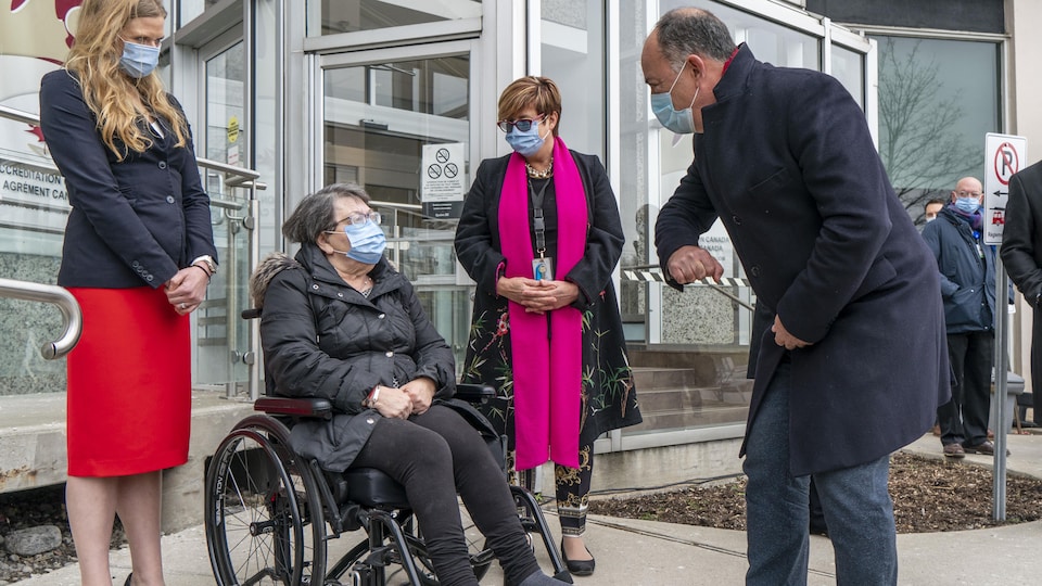 Christian Dubé se tient debout devant une femme en fauteuil roulant à l'entrée de l'établissement. 