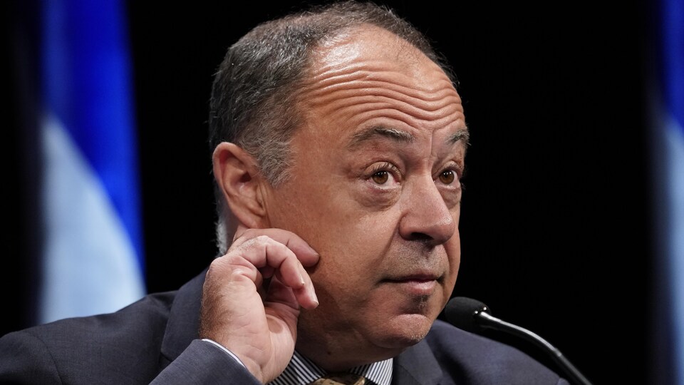 Christian Dubé semble tendre l'oreille lors d'une conférence de presse.