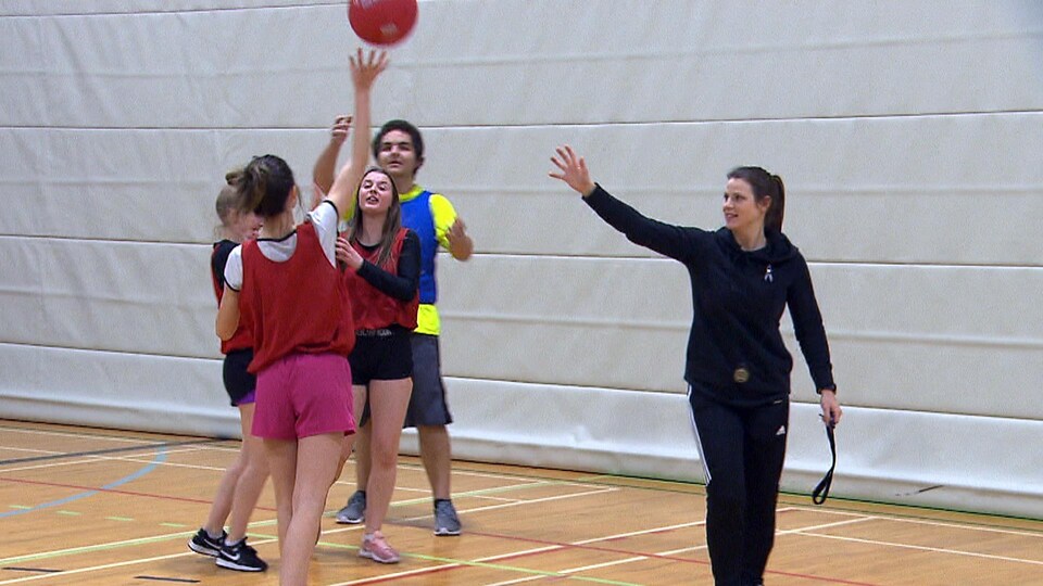 Ils jouent au ballon sous le regard de leur professeure.