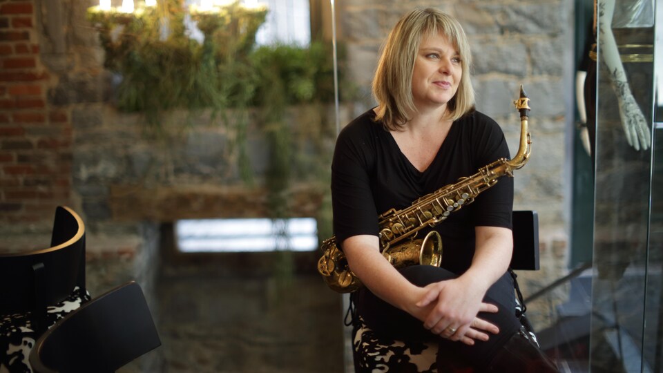 une femme assise avec un saxophone sur les genoux
