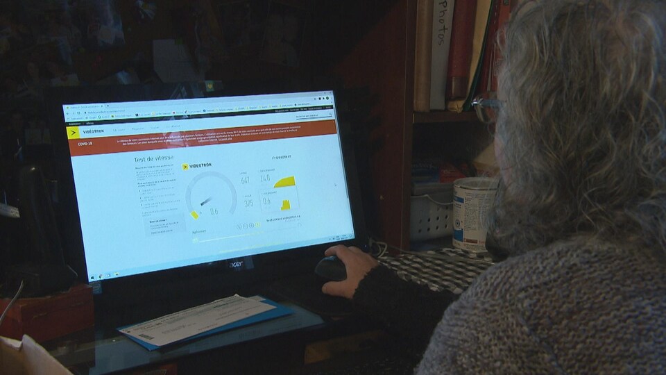 Une dame assise devant son écran d'ordinateur.
